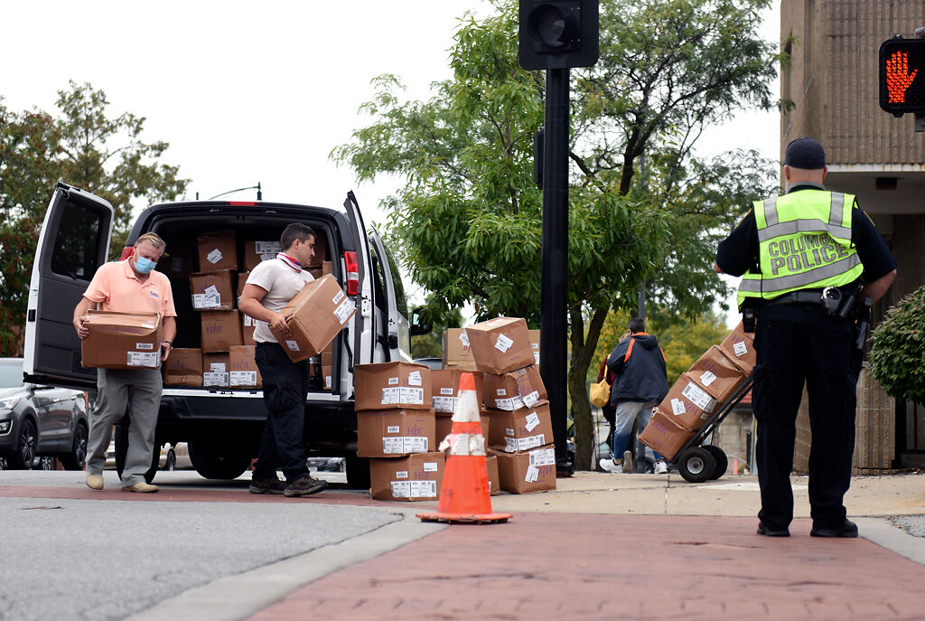 Officer Brad Wolf, right, directs traffic while Walter Domanski and Pito Lopez unload boxes